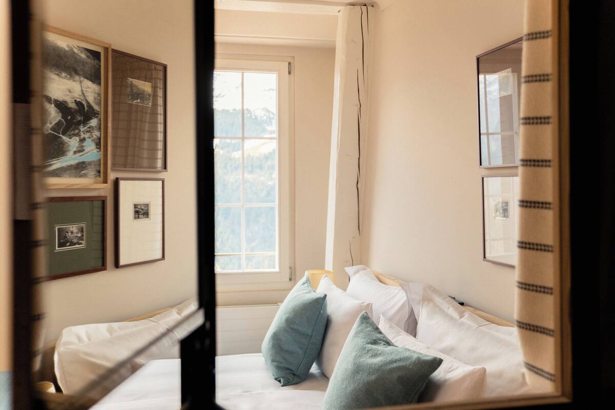 Une chambre à coucher avec un lit, des oreillers et des tableaux encadrés accrochés au mur.