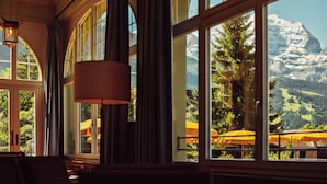 Una habitación con amplios ventanales que dan a una montaña y vistas a sombrillas exteriores.