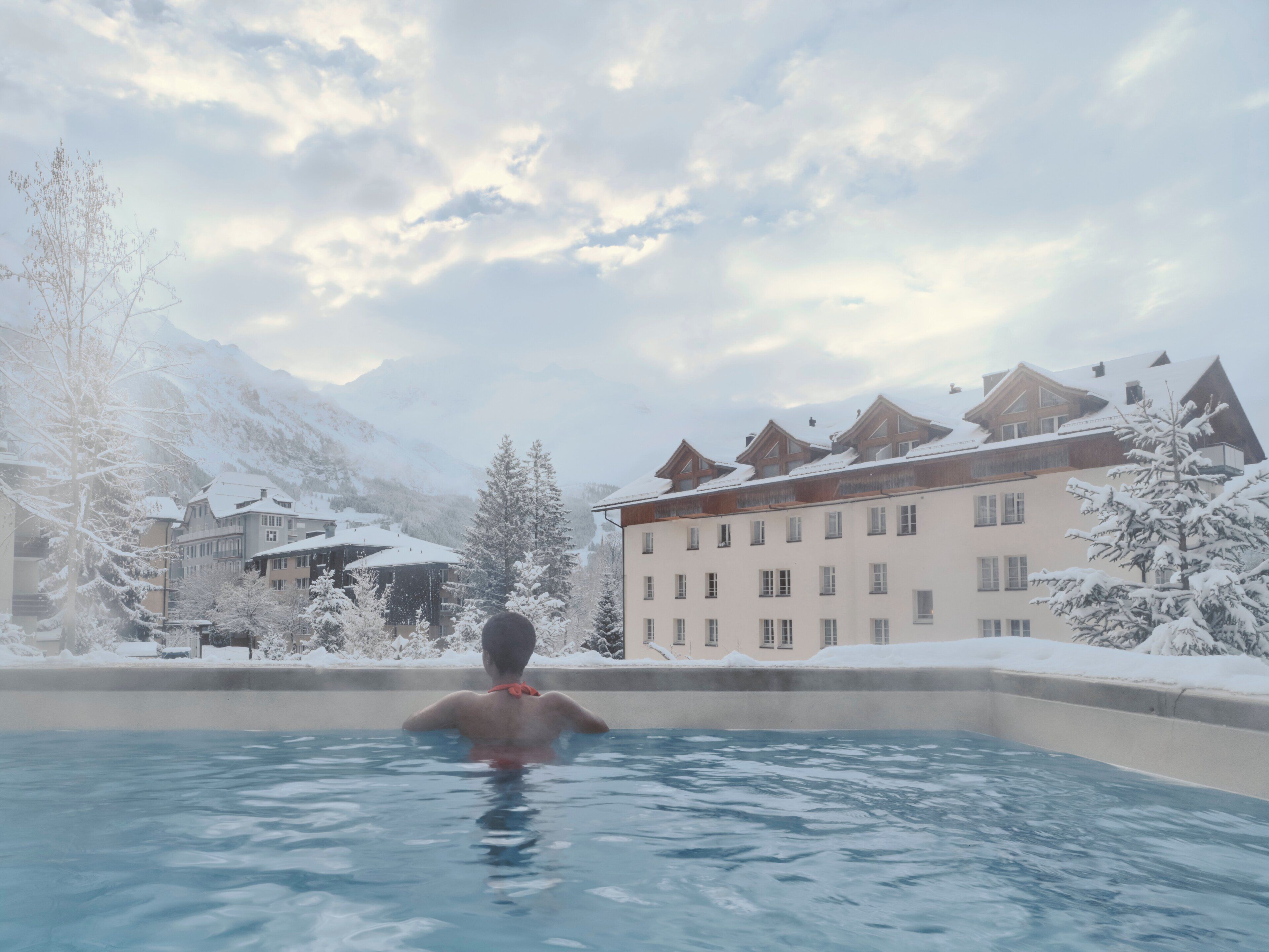 Alberca techada, alberca al aire libre y sombrillas en la alberca