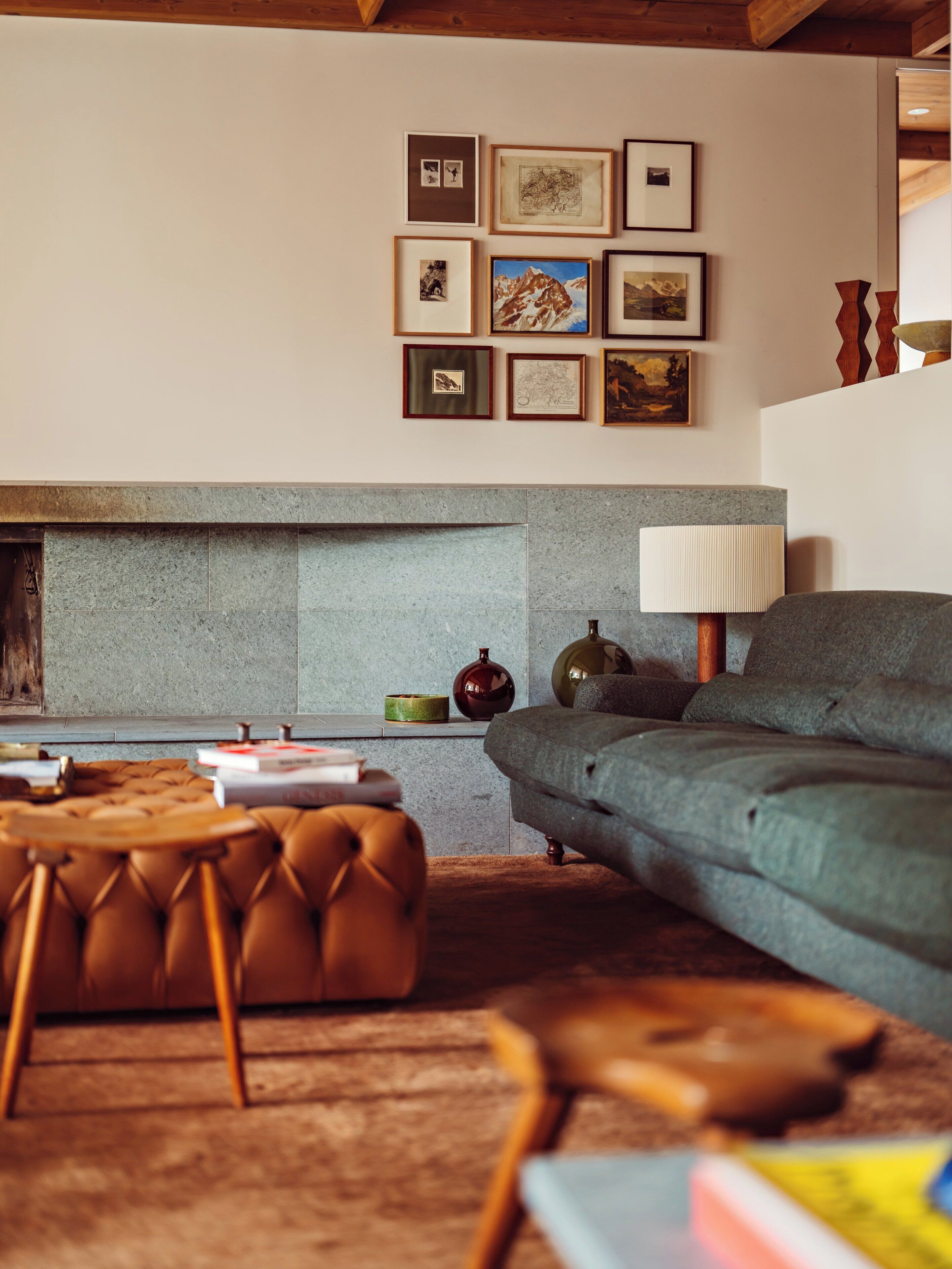 Una sala de estar acogedora con chimenea, un sofá, una mesa de centro y una colección de cuadros en la pared.