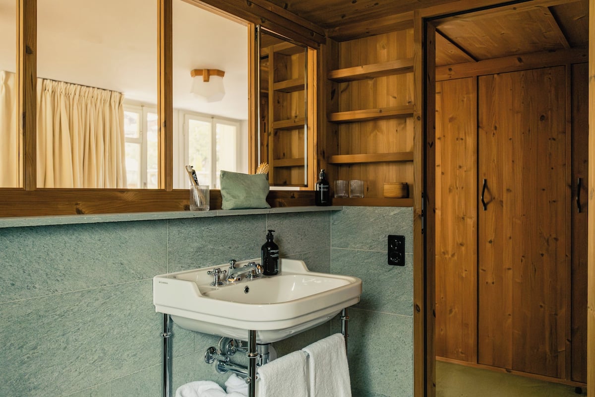 Une salle de bain avec un intérieur en bois, un lavabo blanc et un miroir au-dessus.