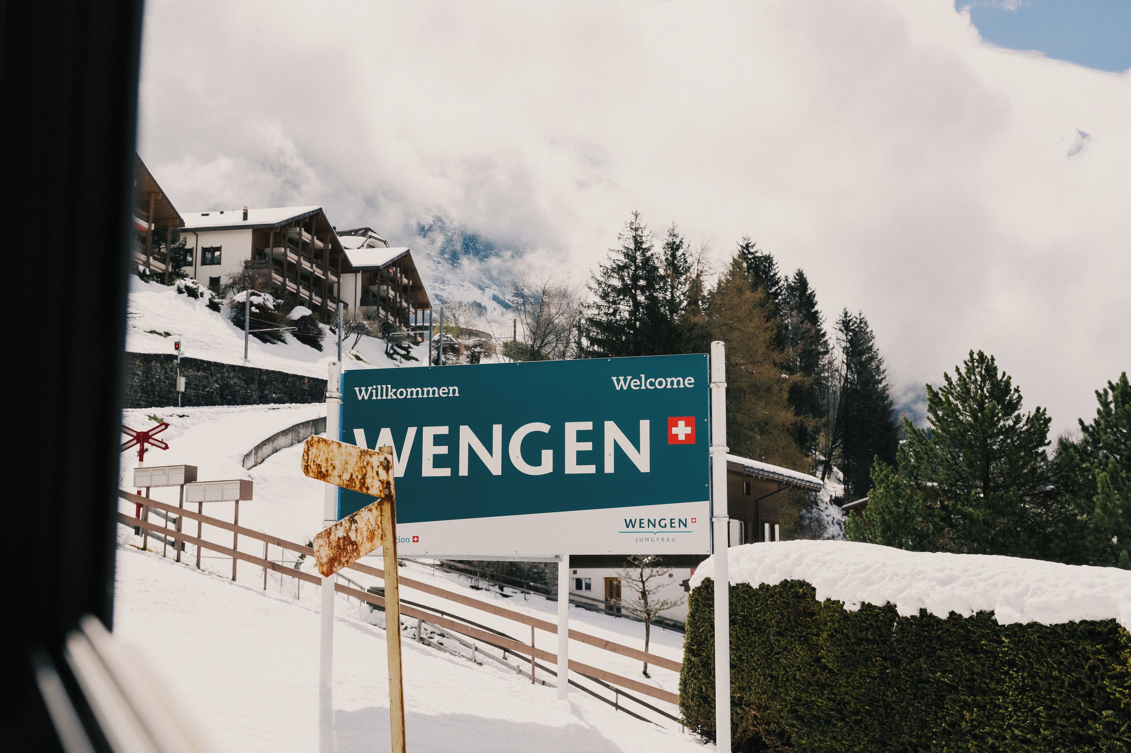 Un panneau accueillant les visiteurs à Wengen, représentant un paysage enneigé et une chaîne de montagnes en arrière-plan.