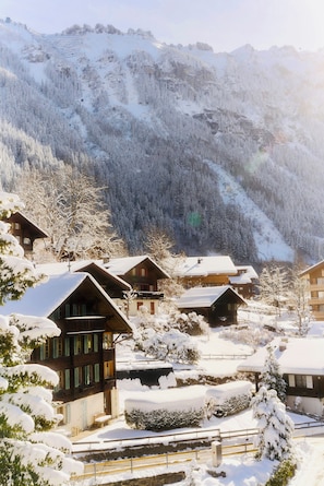 Un pueblo nevado en la montaña con edificios tradicionales de madera y una vista despejada de las montañas circundantes.