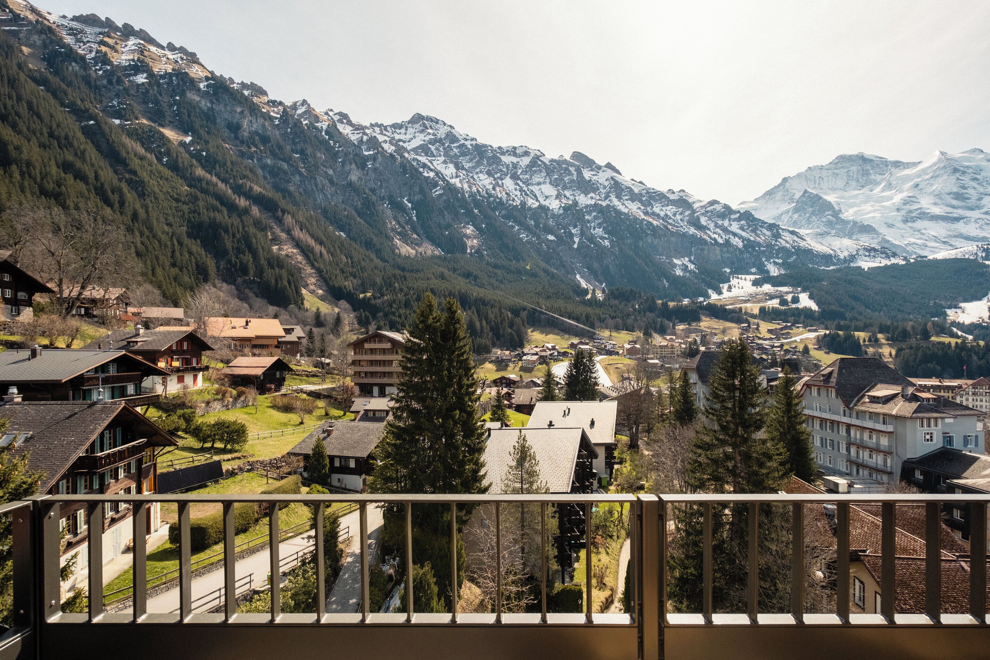 A mountain town with traditional buildings, a clear road, and snow-capped mountains in the background.