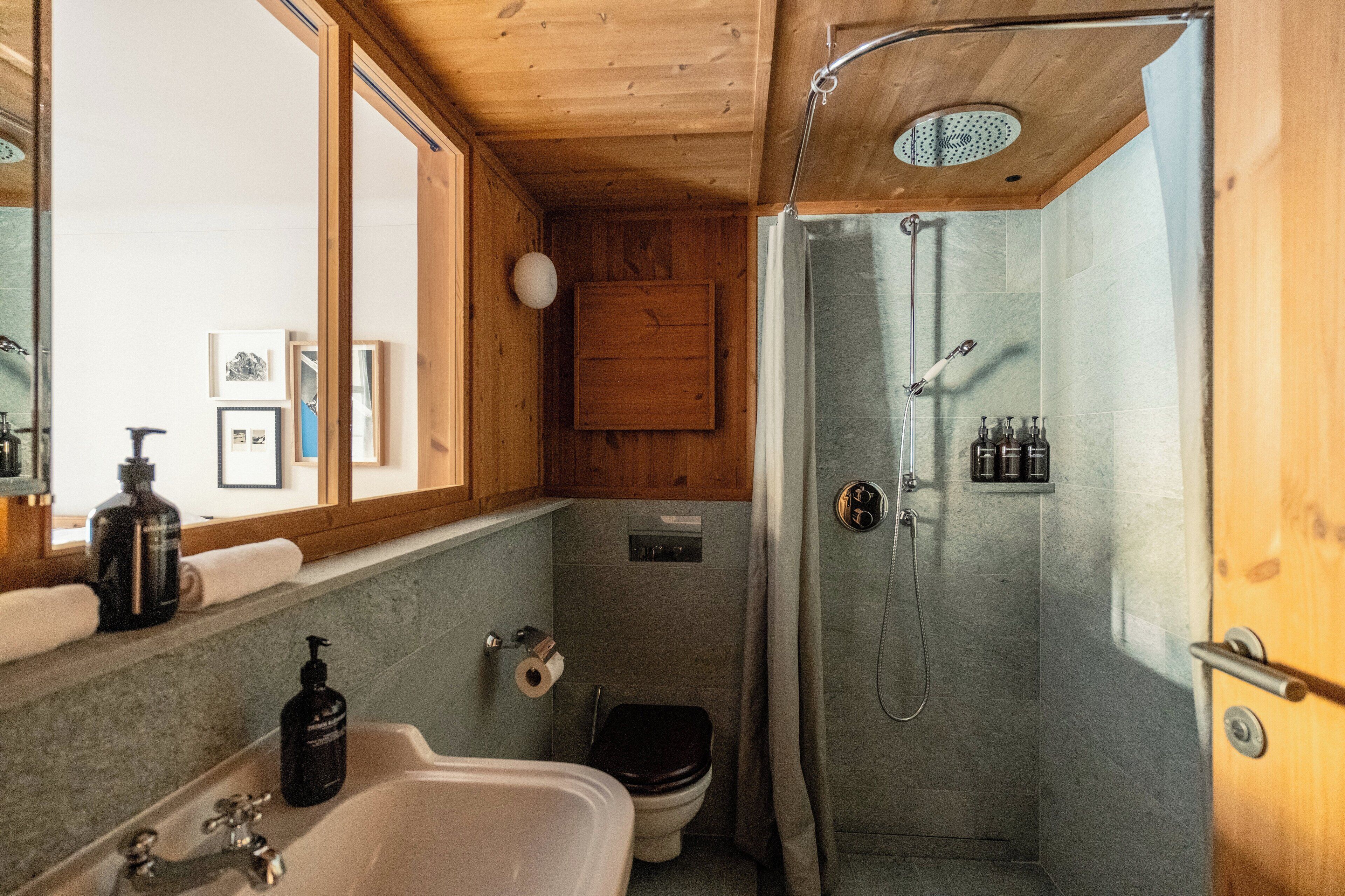 A bathroom with a shower, toilet, sink, and wooden cabinets.