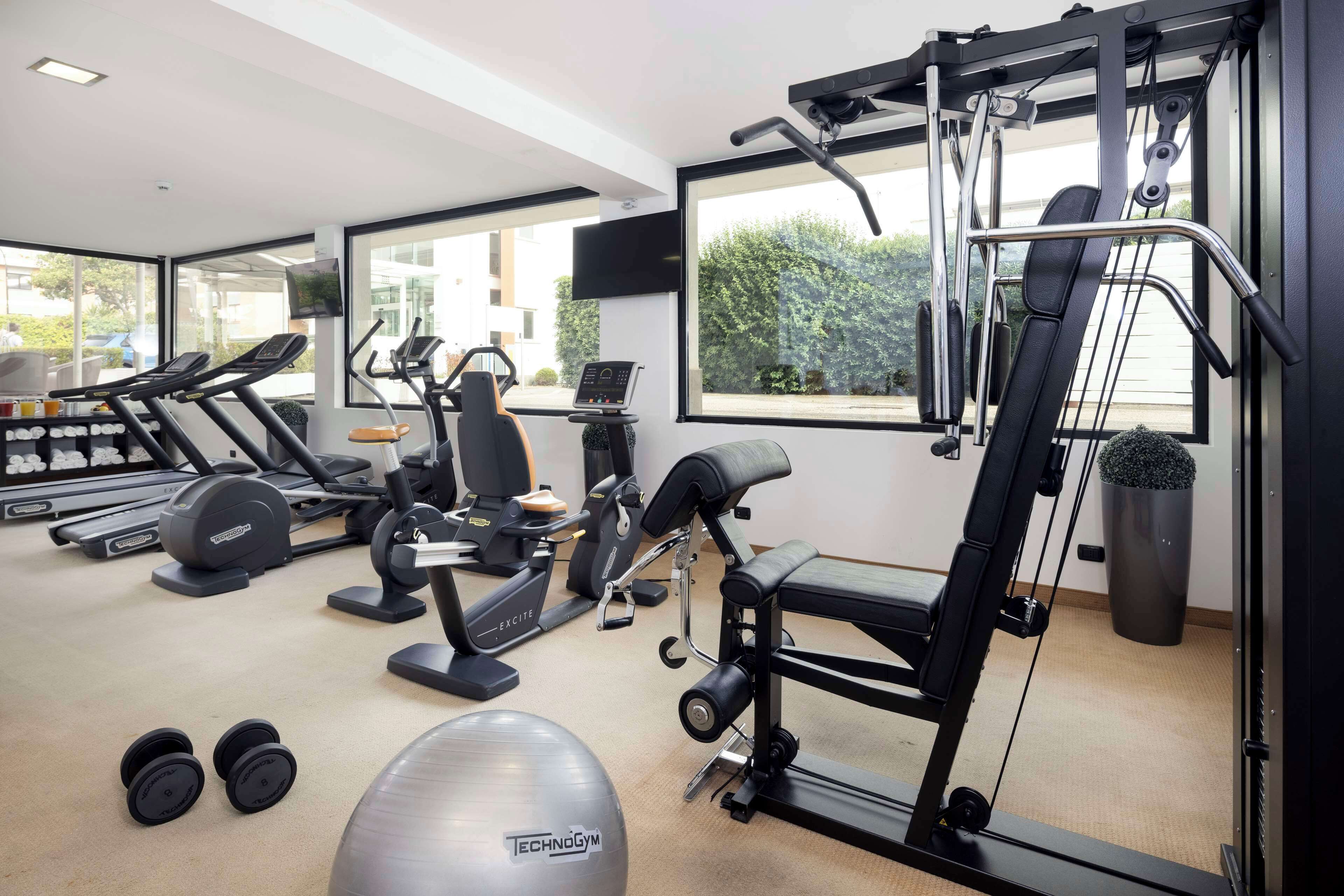 Un gimnasio moderno con máquinas de cardio, pesas libres y banco para pesas.