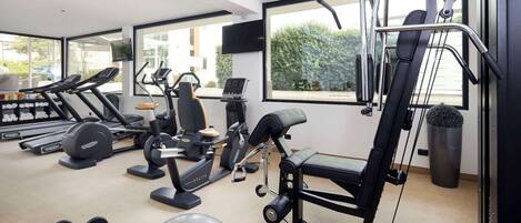 A modern gym with cardio machines, free weights, and a weight bench.