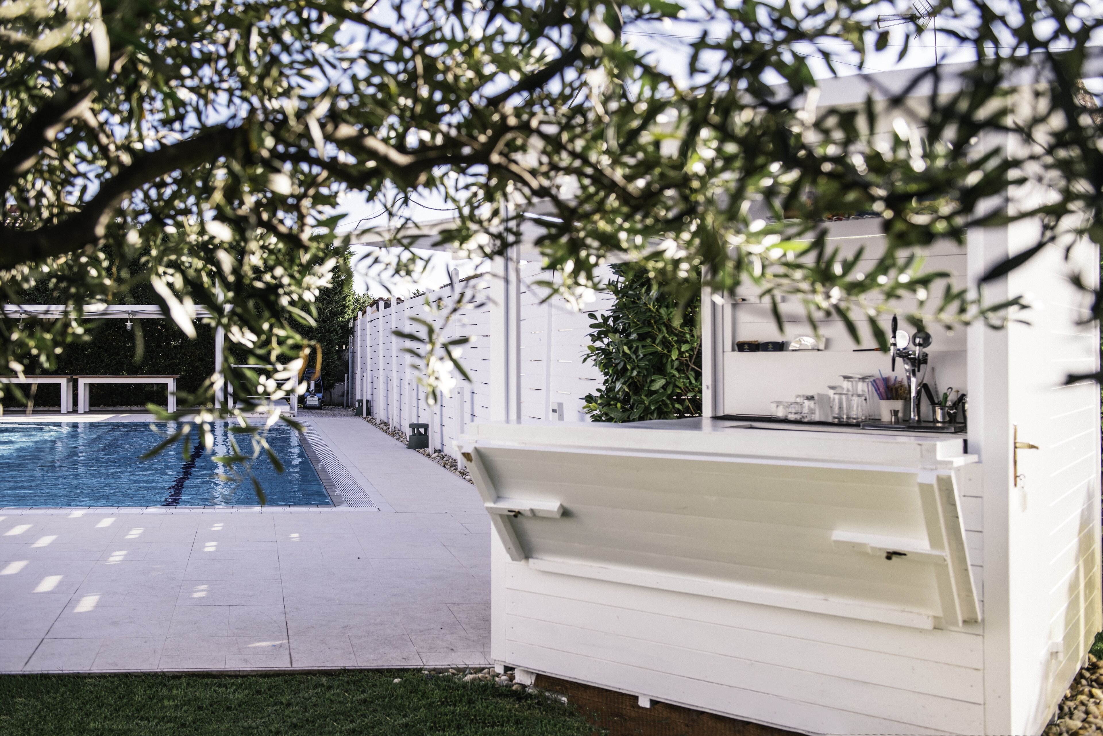 A swimming pool with a white deck and a covered area with a counter.