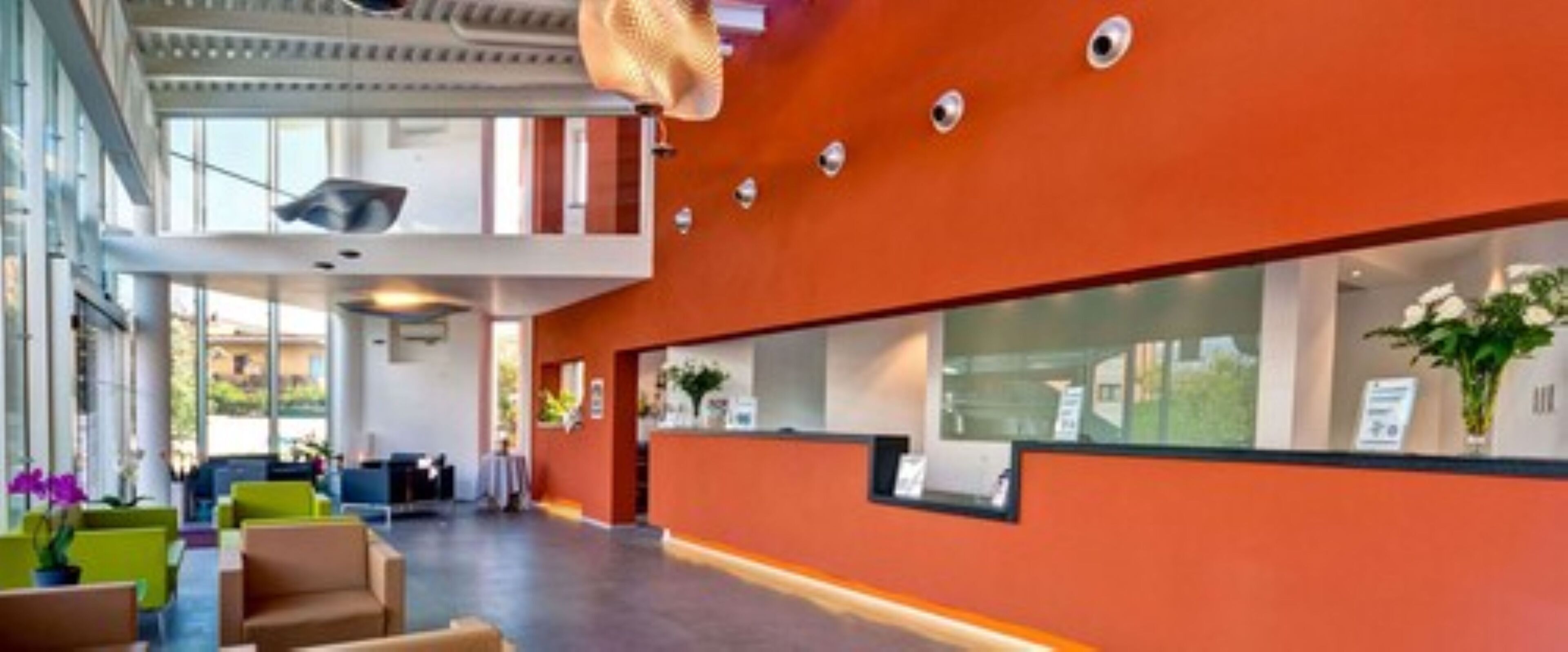A modern hotel lobby with a high ceiling, a reception desk, and seating areas.