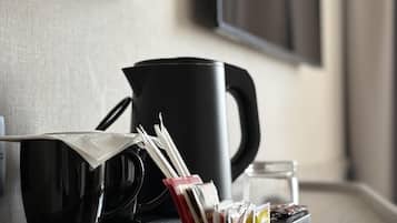 Una zona de cocina con una cafetera, una taza y una bandeja con cápsulas de café.