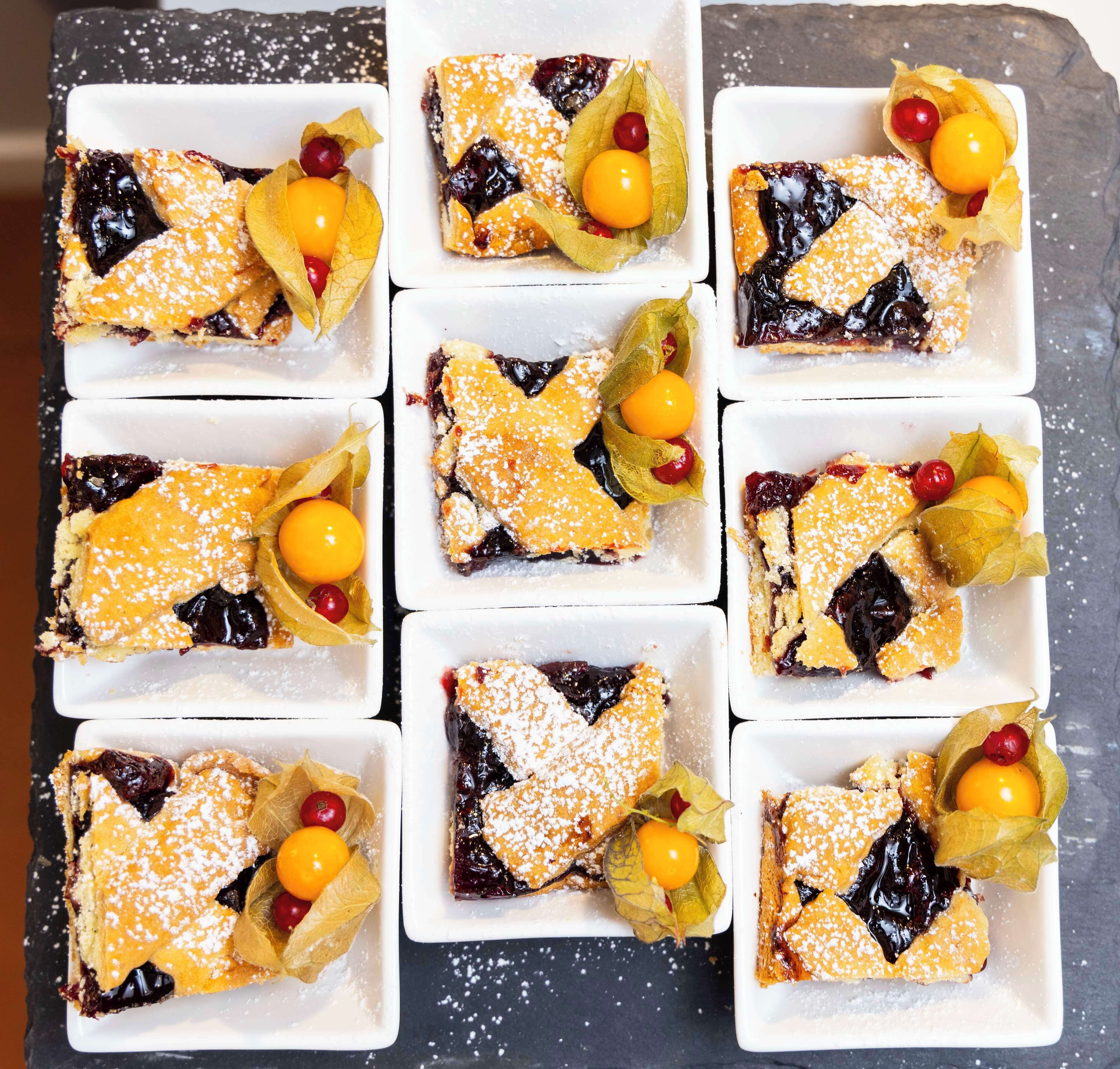 A tray of desserts with powdered sugar and cherries.