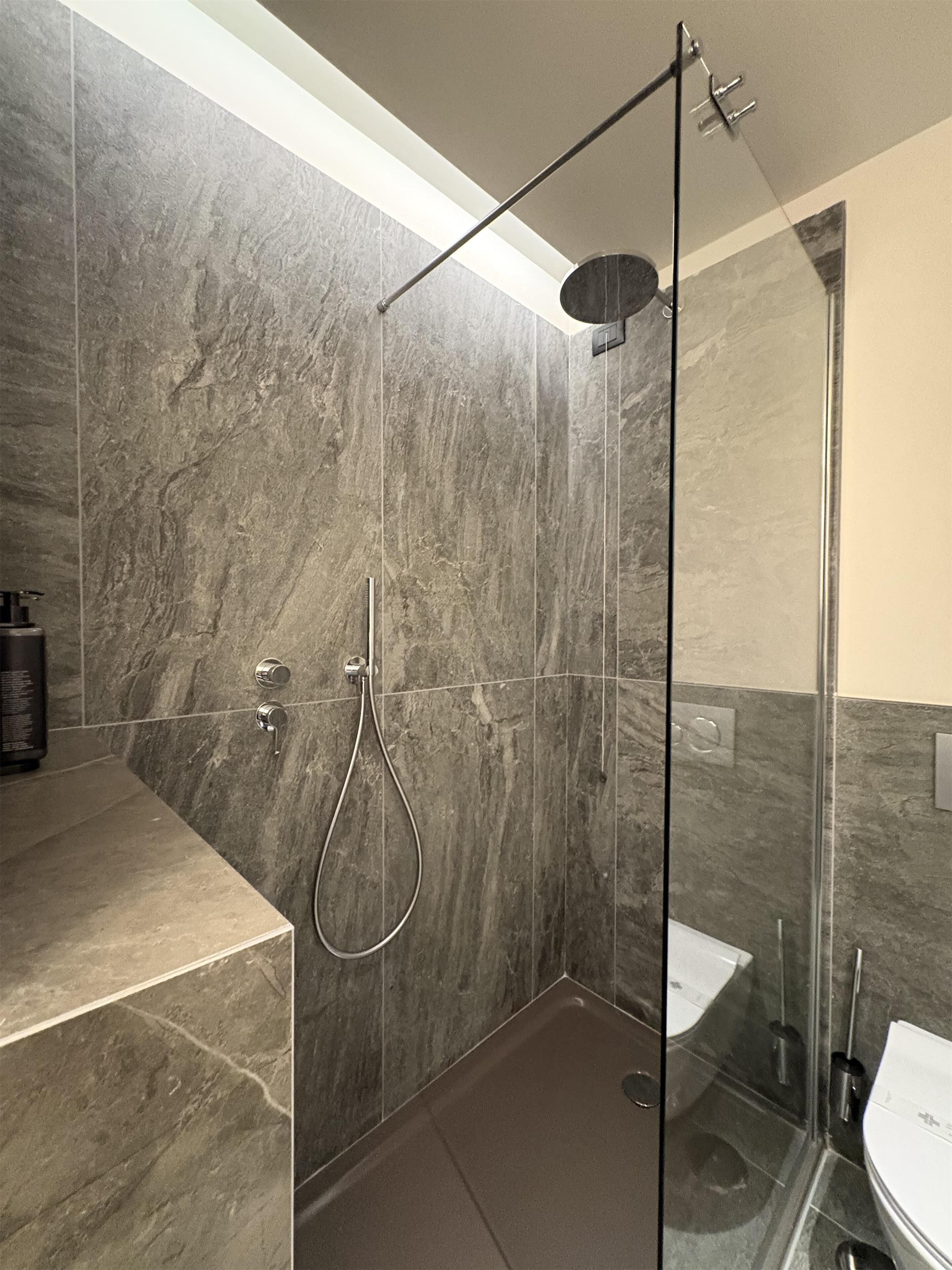Une salle de bain moderne dotée d’une douche à parois de verre, de toilettes et d’un lavabo.