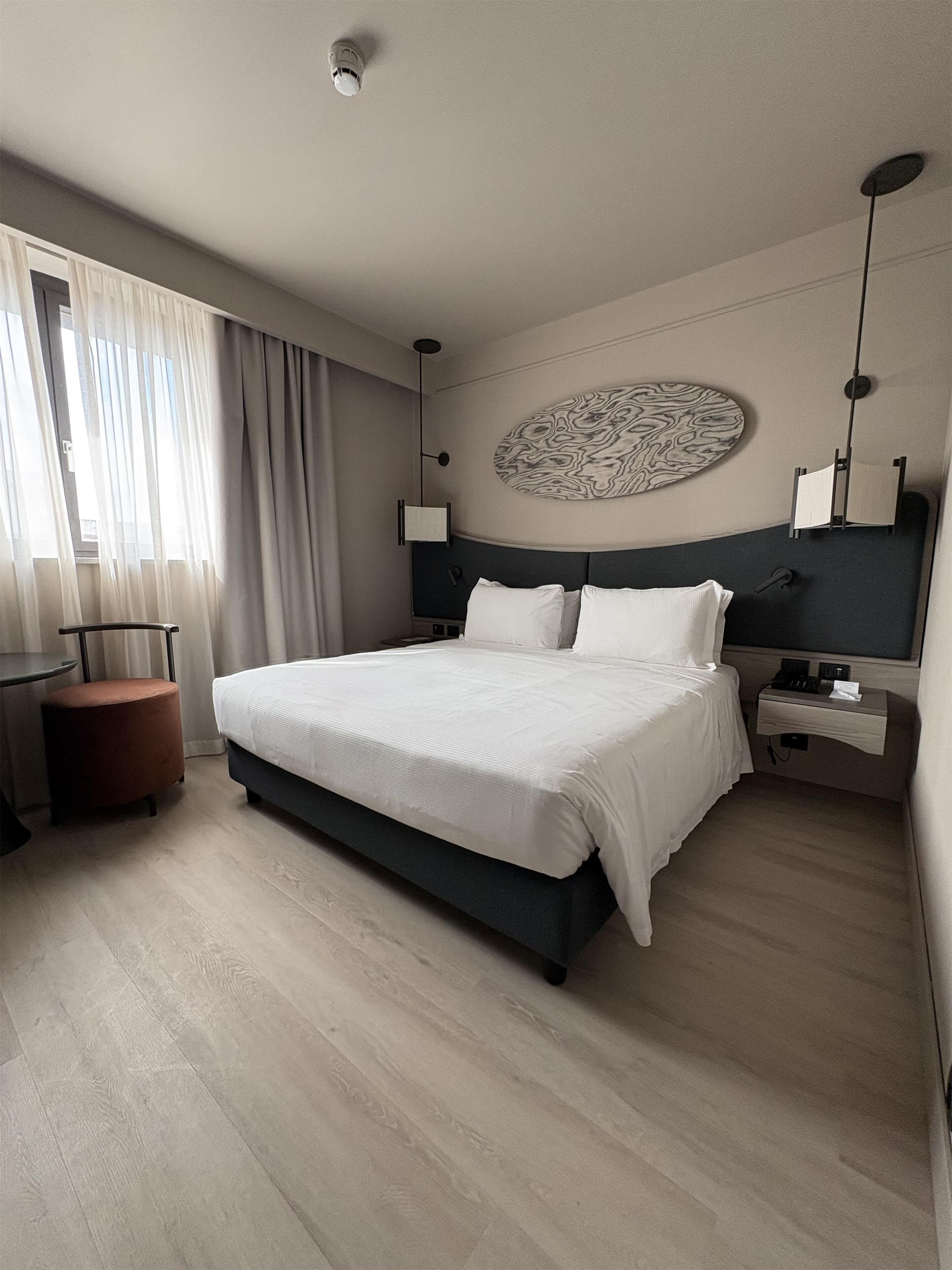 Una habitación de hotel moderna con una cama grande, un adorno circular en la pared, un escritorio y una silla.