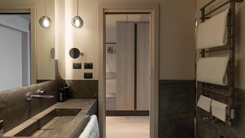 Ein modernes Badezimmer mit Waschbecken, Spiegel, Handtuchhalter und Duschbereich.