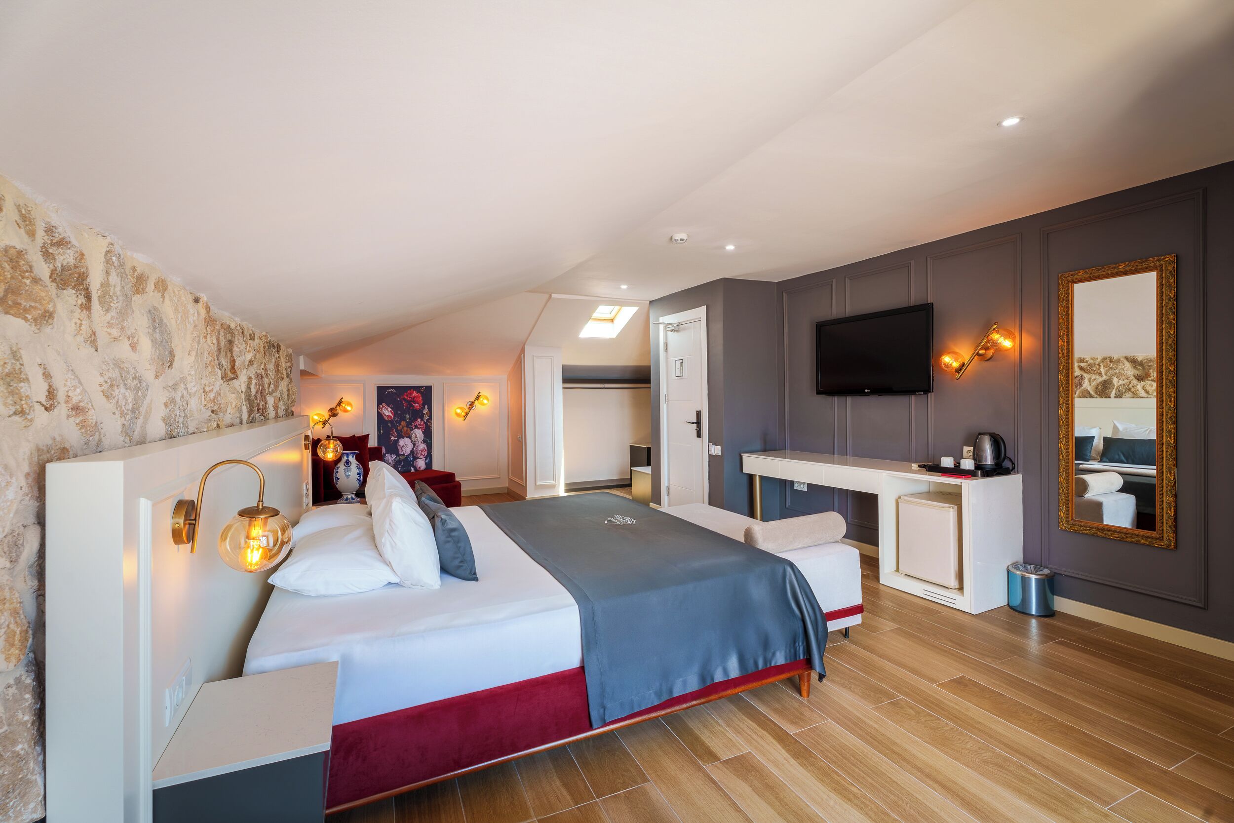 Une chambre à coucher moderne avec un lit, des tables de chevet, un bureau, une télévision et un miroir.