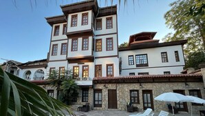 Un edificio de varios pisos con zona de piscina, mobiliario exterior y fachada de piedra.