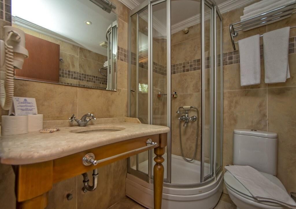 Een badkamer met een wastafel, spiegel, douche en toilet.