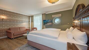 Una habitación de hotel con una cama grande, un sofá, una mesita y un televisor.