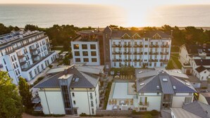 A multi-story residential building with balconies, a swimming pool, and a view of the sea.