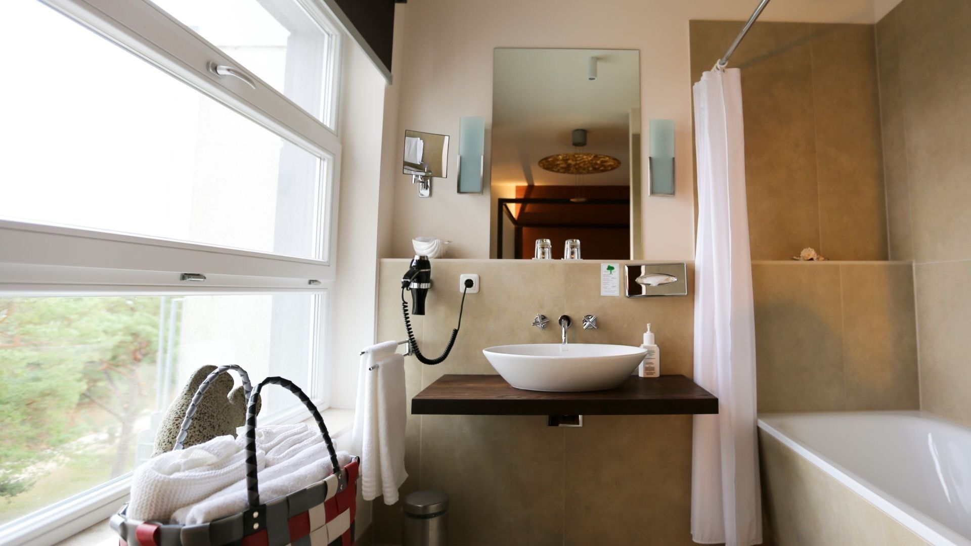 A bathroom with a large window, a sink, a mirror, a towel rack, and a shower curtain.