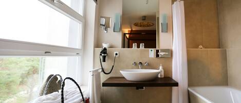 A bathroom with a large window, a sink, a mirror, a towel rack, and a shower curtain.