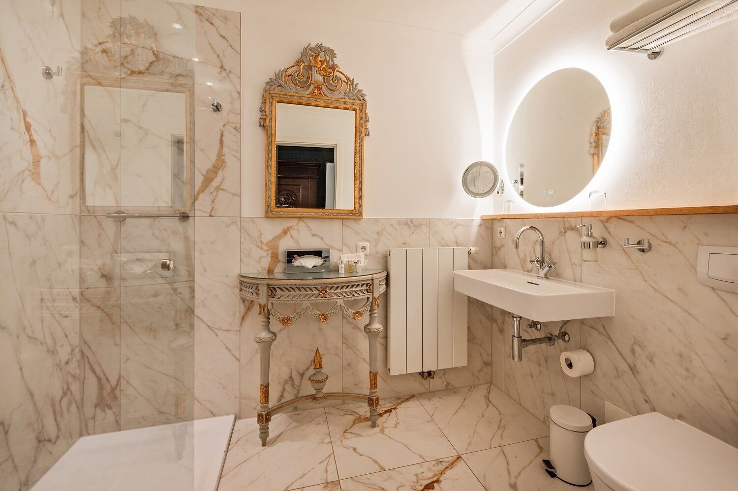 Une salle de bain avec un sol en marbre, un meuble-lavabo avec un miroir, un évier et des toilettes.