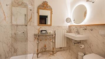 Une salle de bain avec un sol en marbre, un meuble-lavabo avec un miroir, un évier et des toilettes.