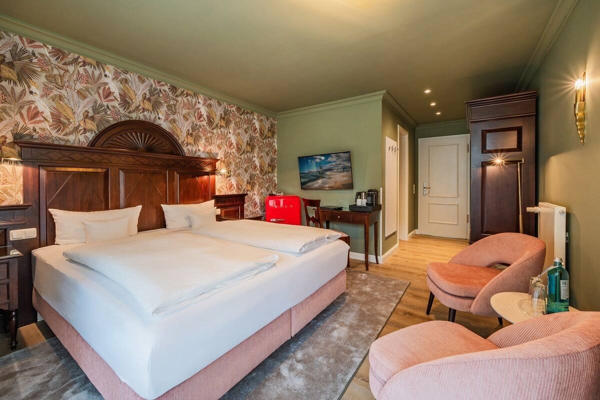 Ein Hotelzimmer mit einem großen Bett, einem Schreibtisch, einem Stuhl und einem Bild an der Wand.