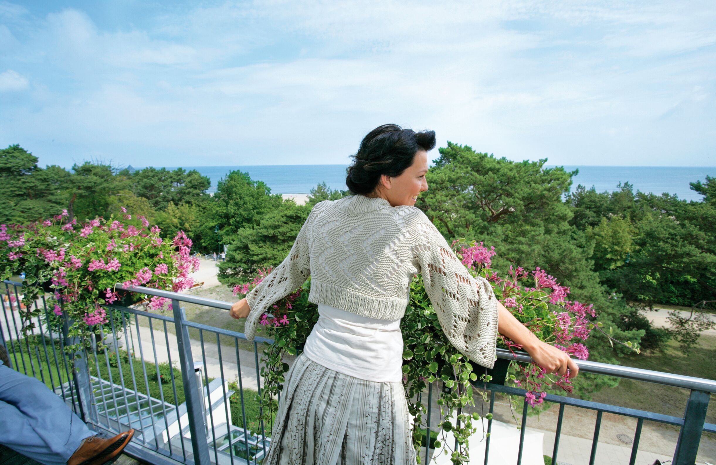 A balcony with a view of the sea and greenery.