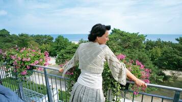 A balcony with a view of the sea and greenery.