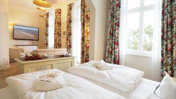 Habitación de hotel con dos camas, un escritorio, un televisor y cortinas estampadas.