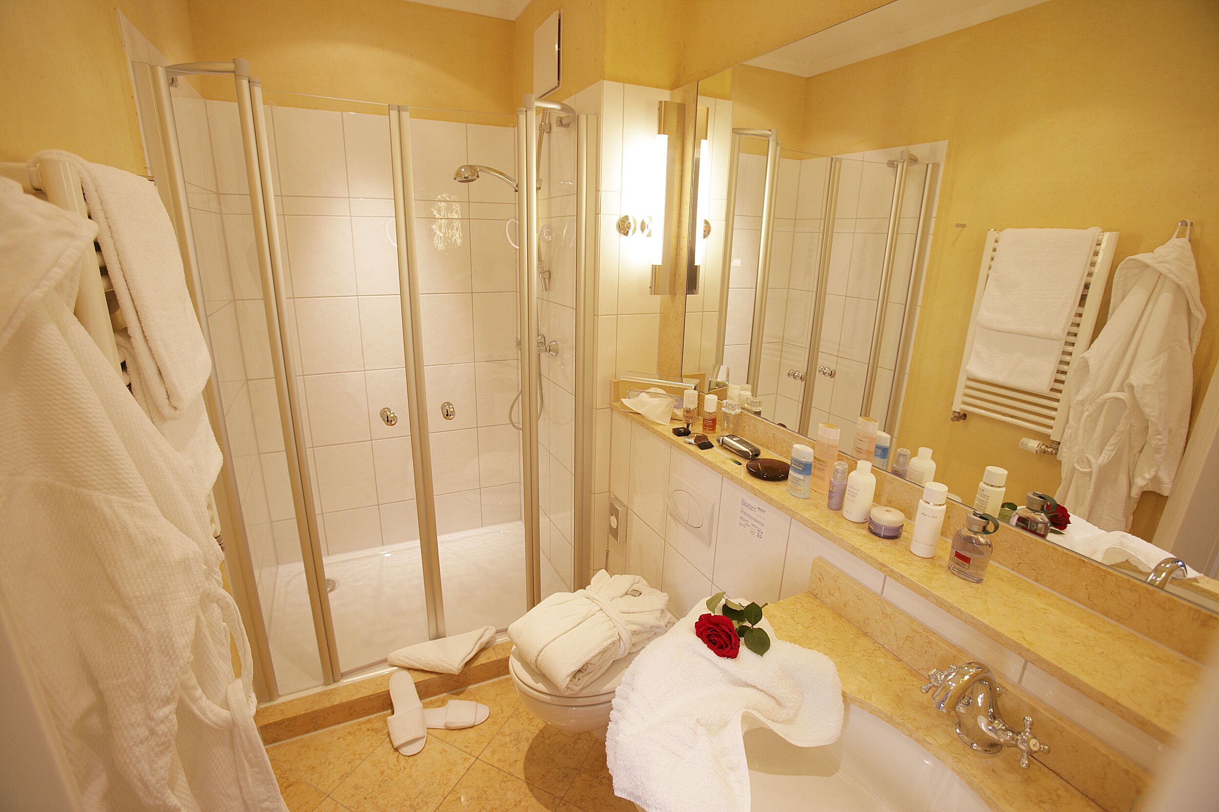 Un bagno con doccia vetrata, lavabo con specchio e diversi asciugamani.