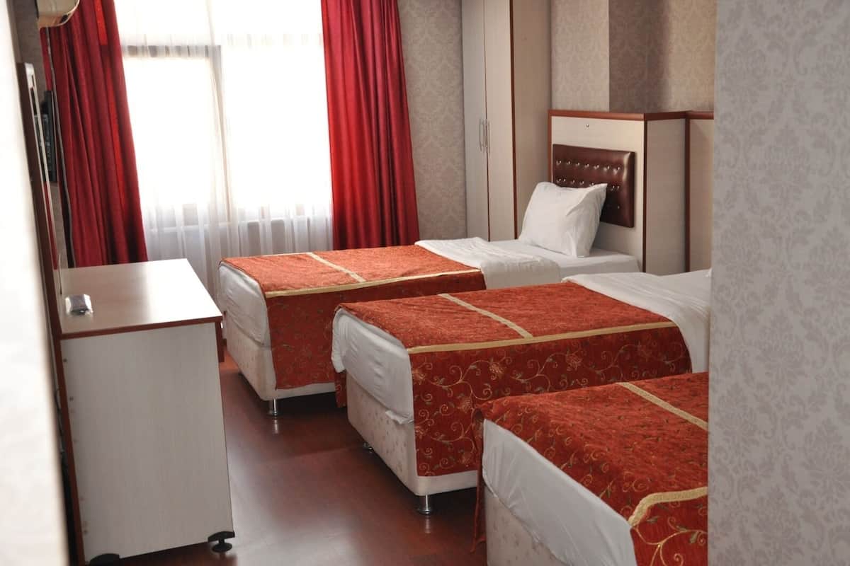 Hotellihuone, jossa on kaksi sänkyä, työpöytä ja patteri.