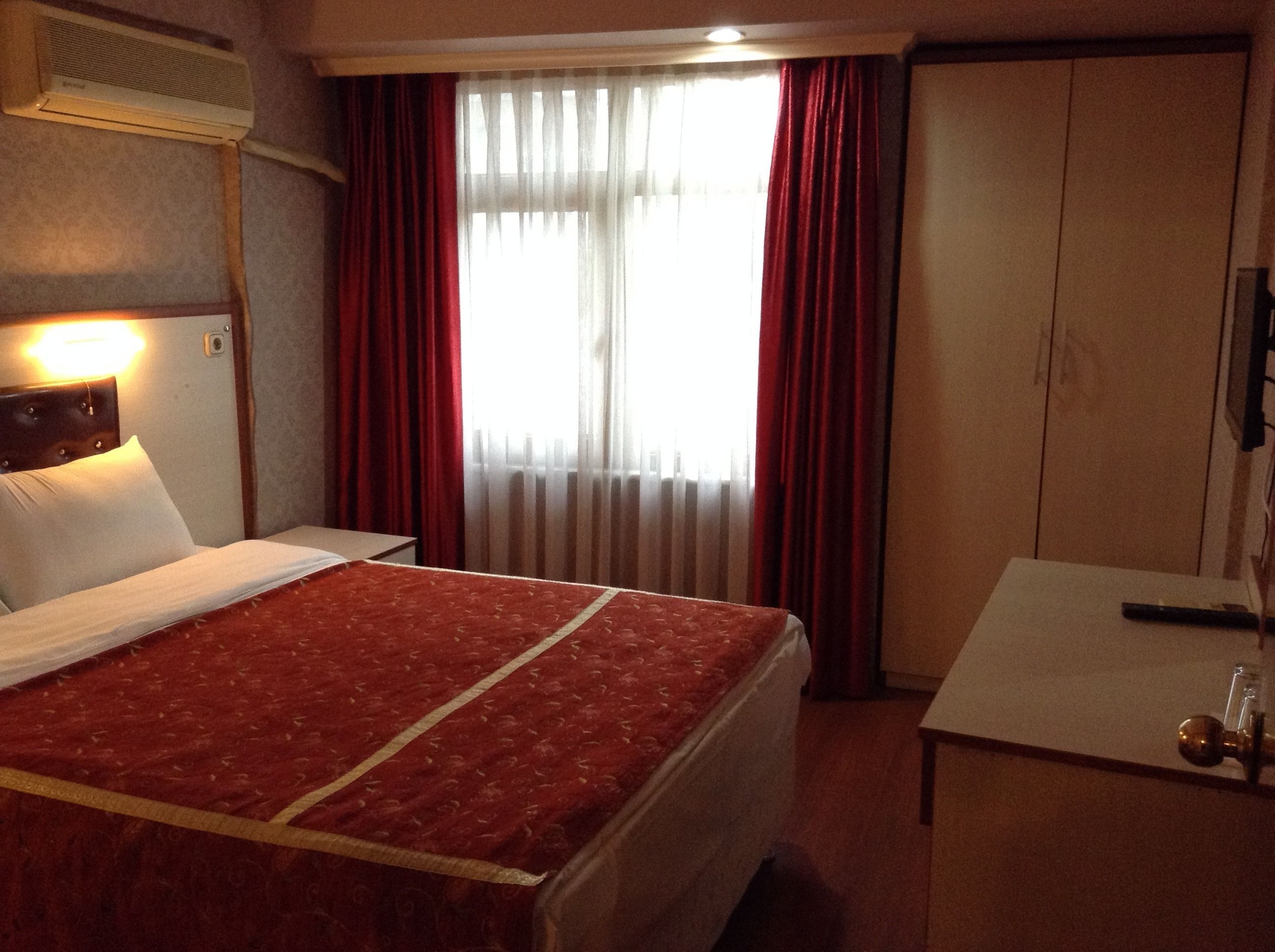A hotel room with a bed, a desk, and a wardrobe.