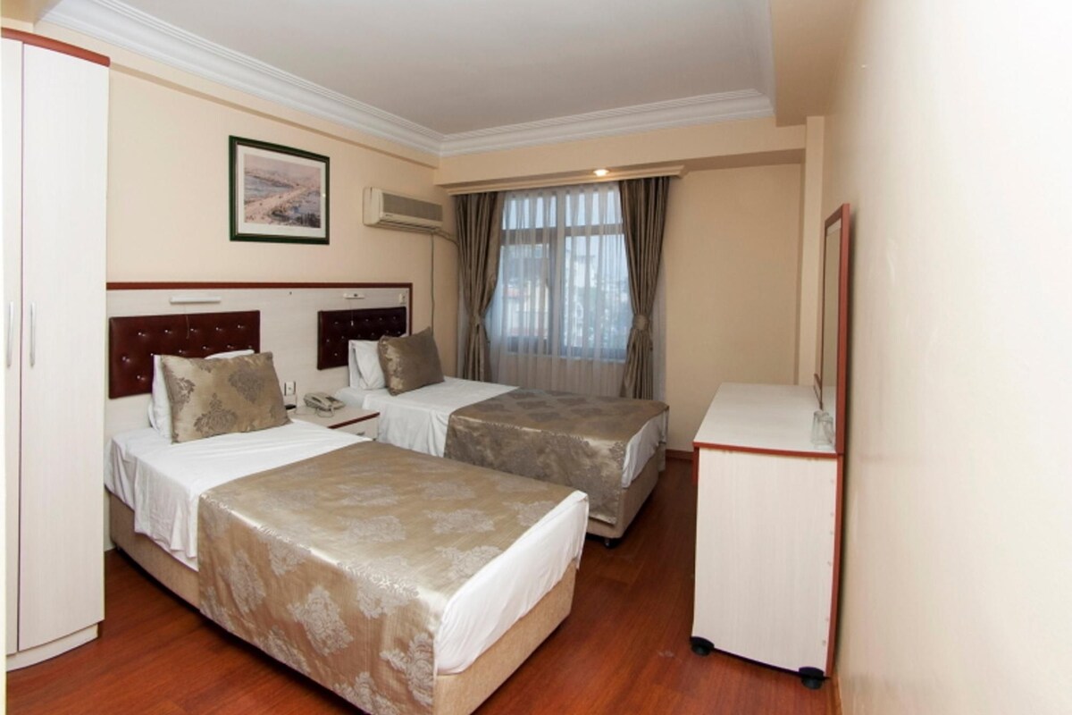 A hotel room with two beds, a desk, and a wardrobe.