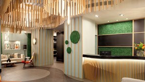 A modern reception area with a curved reception desk, vertical wooden slats, and green wall accents. -  Zeus Essence Bucharest, Trademark Collection by Wyndham (Bucharest)