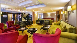 A hotel lobby with red and yellow seating, a staircase, and a reception area. - Hotel Grand Emin (Istanbul)