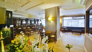 A hotel lobby with wooden flooring, a bar area, and seating arrangements. - Hotel Grand Emin (Istanbul)