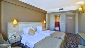 A hotel room with two beds, a nightstand with a phone, and a lamp. - Hotel Grand Emin (Istanbul)