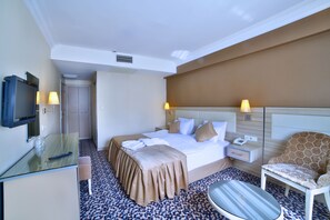 A hotel room with a bed, bedside table, chair, and a small table with a remote control. - Hotel Grand Emin (Istanbul)