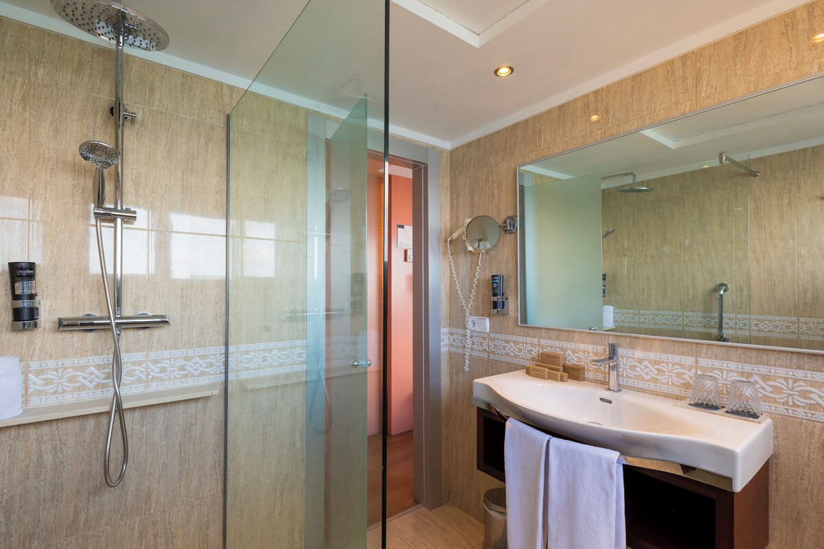 A modern bathroom with a glass-enclosed shower, a sink with a mirror, and a towel rack.