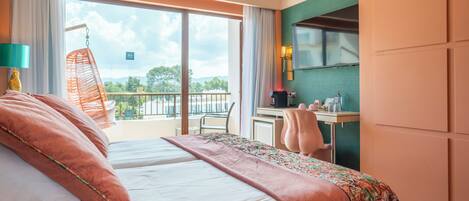 A bedroom with a large bed, a desk, and a view of the outdoors.