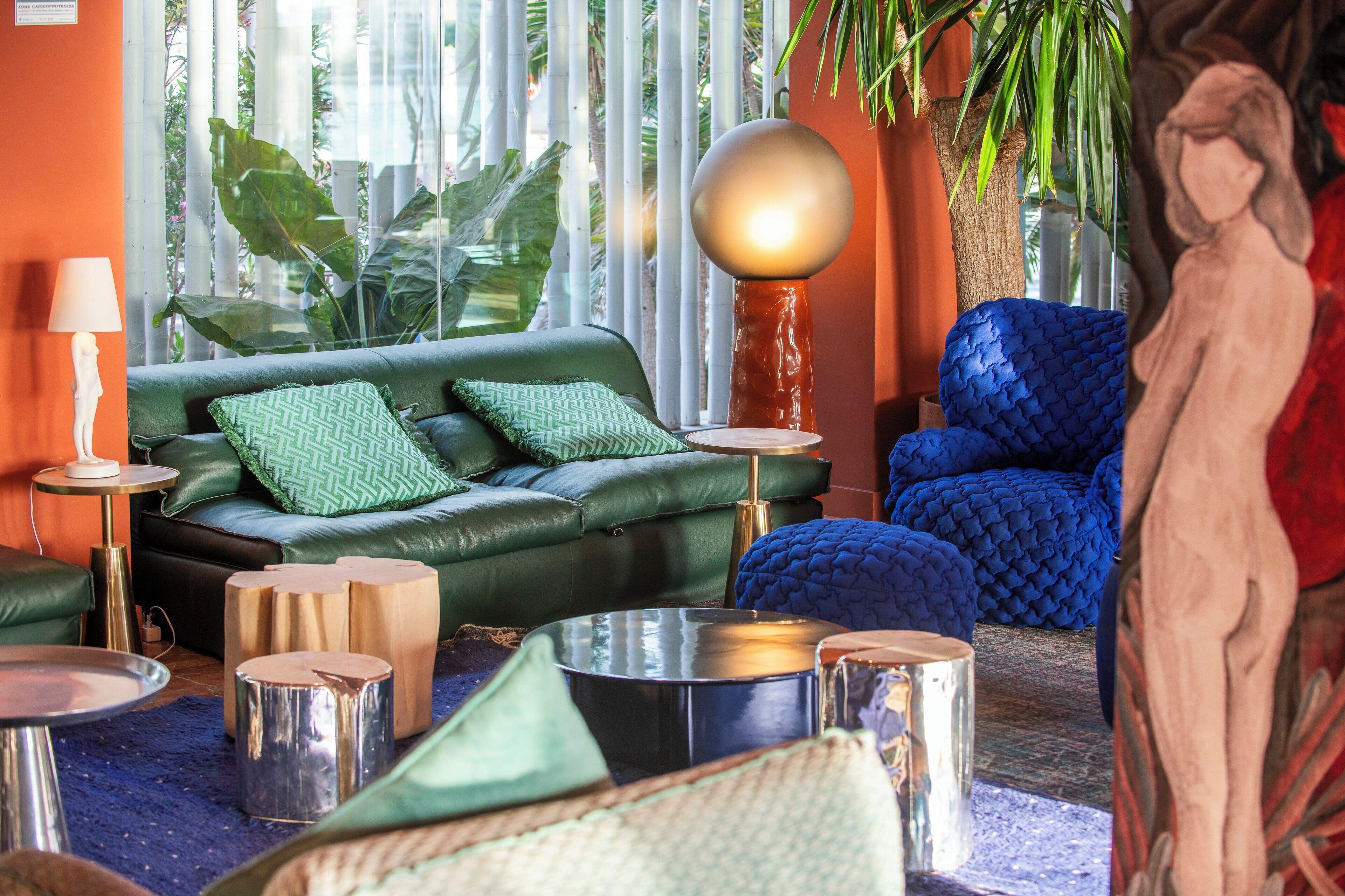 A modern living room with a green sofa, blue armchair, and a round table.
