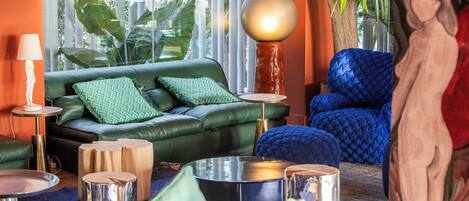 A modern living room with a green sofa, blue armchair, and a round table.