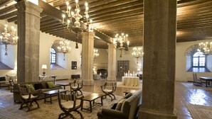 Un hall d’entrée spacieux, doté de hauts plafonds, de lustres et de colonnes de style classique. Aménagé avec des canapés, des fauteuils et des tables, cet espace est agrémenté d’un tapis à motifs et d’une cheminée.