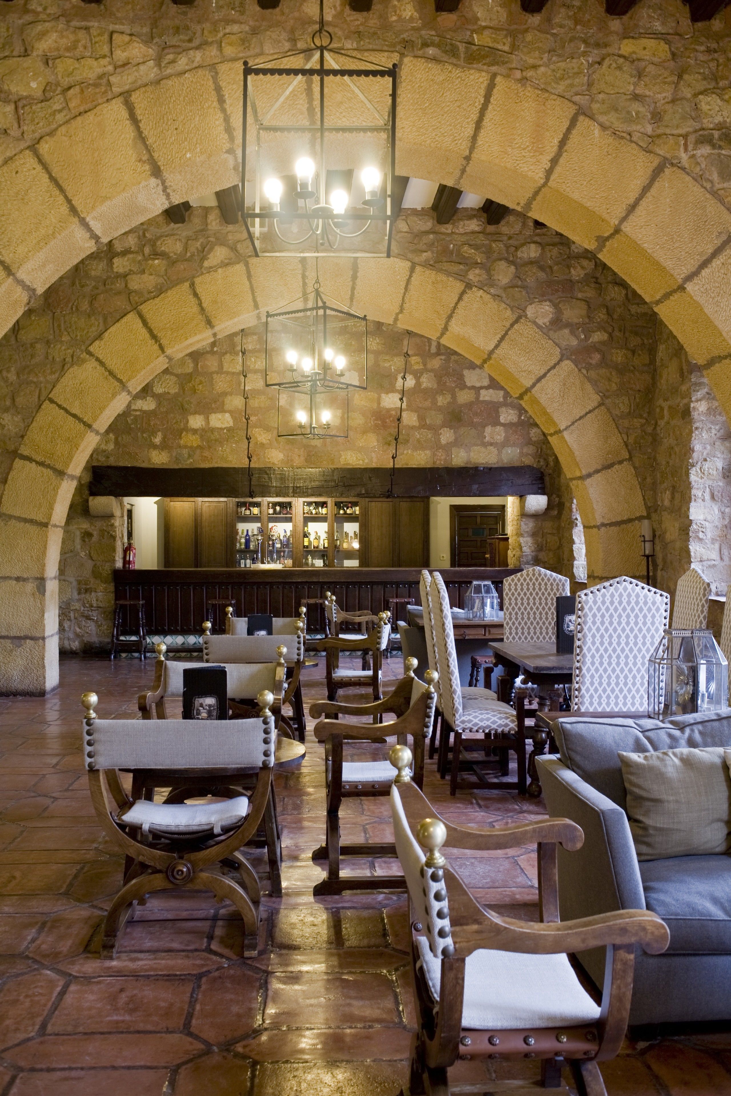 A stone-walled bar area with wooden furniture and a chandelier.