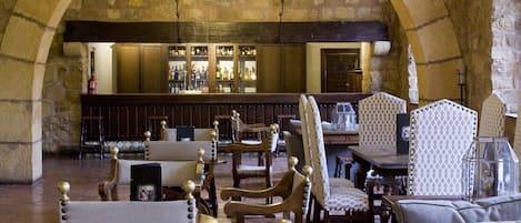 A stone-walled bar area with wooden furniture and a chandelier.