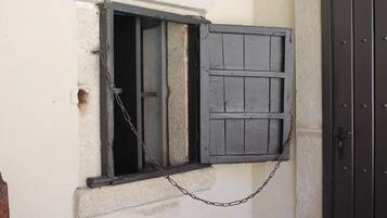 A window with a wooden shutter and a chain.