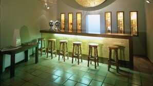 Un área de bar con un espejo redondo, taburetes de madera y suelo de baldosas.