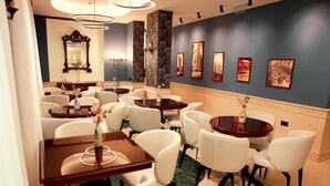 A dining area with round tables and white chairs, a large mirror, and framed pictures on the wall. - Zeus Essence Bucharest Opera (Bucharest)